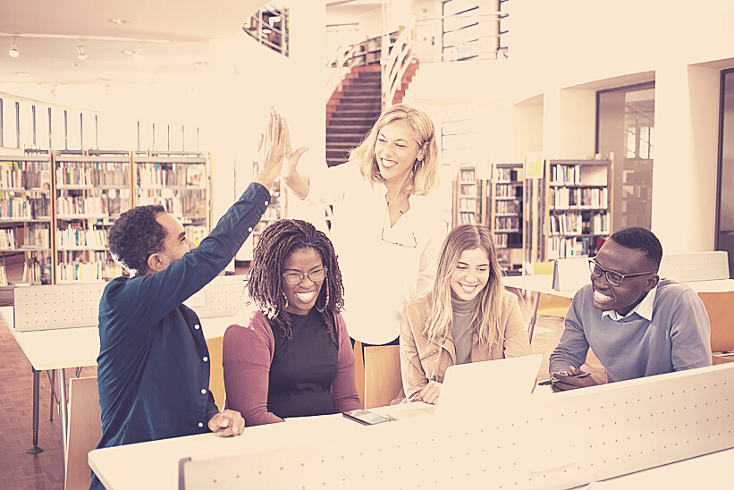 Cheerful multiethnic students having high five with teacher